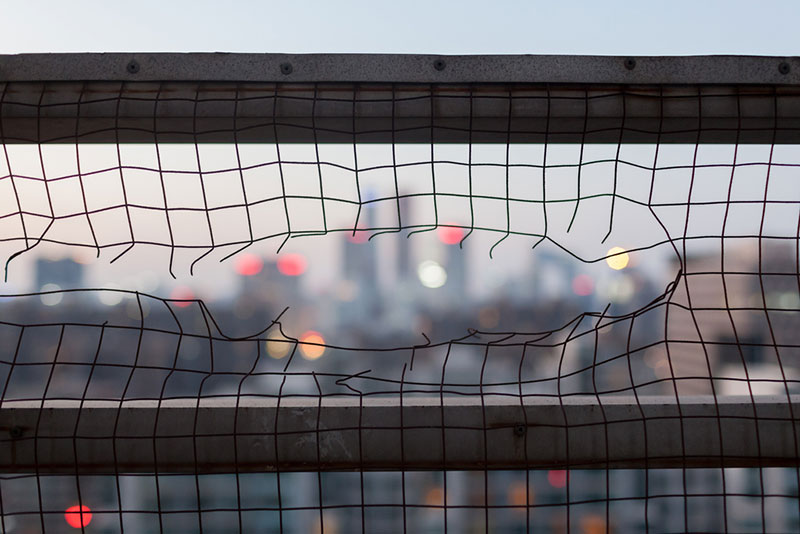 Image of a wire fence with a hole torn in it
